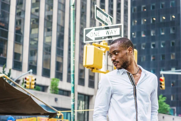 Genç Afrikalı-Amerikalı adam, iki sokak Manhattan, New York, dönüm başının etrafında, düşünme kavşakta ayakta beyaz gömlek giyiyor. Yüksek binalar, stree işaretleri, One Way, arka plan üzerinde