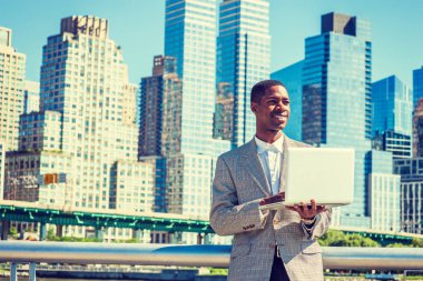 Mutlu genç Afro-Amerikan seyahat, New York City'de iş işadamı dizüstü bilgisayar üzerinde çalışan iş bölgesi Manhattan'ın, ayakta giyen desenli ceket, beyaz gömlek, gülümseyen