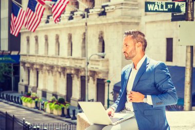 Seyahat, New York City bölgesindeki çalışma, Wall Street işaretiyle bina, dizüstü bilgisayarda çalışarak, düşünme ofis dışında sokakta oturan mavi ceket giyiyor sakallı genç Avrupa iş adamı