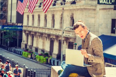 Genç İspanyol Amerikan kolej seyahat, New York City bölgesindeki saç topuz ile eğitim gözlük, öğrenci dizüstü bilgisayar üzerinde çalışan Wall Street'te oturan ceket, kot, kahverengi desenli.