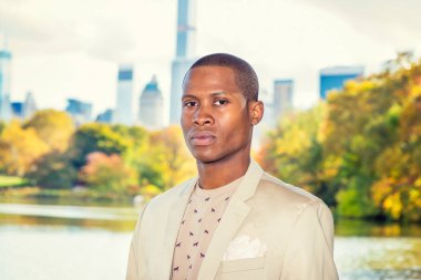 Krem blazer, yakasız kazak, Genç adam soyunma portre genç bir siyah adam büyük bir şehirde bir göl tarafından güvenle sana bakıp duruyor.