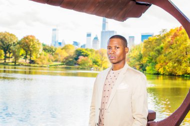 Krem blazer, yakasız kazak, Genç adam soyunma portre genç bir siyah adam büyük bir şehirde bir göl tarafından güvenle sana bakıp duruyor.