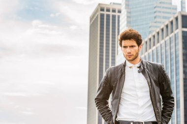 Göklerin sınırı. İnsan gücü. Deri ceket giyiyor laubali bir genç yakışıklı işadamı sakallı, iş bölgesinde ayakta, düşünme, arıyorum. Kopya alanı