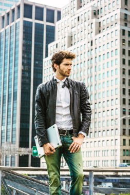 New York'ta ciddi Avrupa iş adamı. Pansuman mavi takım elbise, gömlek, el taşıma dizüstü bilgisayar, sakallı, bir genç adam, seyir, üzgün, sinir bozucu, ifade duyguları rahatsız kaşlarını çattı