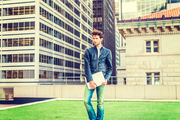 New York'ta eğitim Avrupa yüksek lisans öğrencisi. Siyah deri ceket, kot, dizüstü bilgisayar, taşıyan, iş bölgesinde,'ın bahçesinde duran sakallı bir adam düşünüyorum