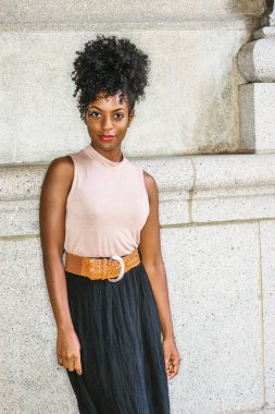 New York'ta genç Afro-Amerikan kadın portresi. Giydiği kolsuz açık renk üst, kahverengi kemer, siyah etek, duvar karşı ayakta afro saç modeli ile Bayan üniversite öğrencisi genç siyah