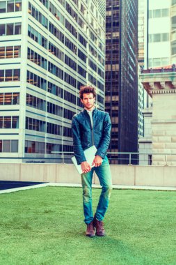 Seyahat, New York'ta çalışma Avrupa iş adamı. Siyah deri ceket, kot, dizüstü bilgisayar, taşıyan, iş bölgesinde, yeşil çim üzerinde duran sakallı genç bir adam düşünüyorum.