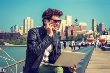 Sitede çalışma zevk iş adamı. Üzerinde deri ceket, güneş gözlüğü, Harbor, bankta oturmuş sakallı bir adam aynı zamanda Evet dizüstü bilgisayarda çalışıyor. Filtre uygulanmış etkisi.