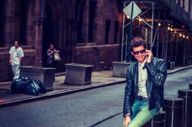 Adam dışarıda arıyor. New York'ta, gülümseyerek, çalışma molası sırasında cep telefonuyla konuşurken sokakta oturan sakallı siyah deri ceket, beyaz Fanila, mavi jeans, güneş gözlüğü, Genç bir adam giyiyor.