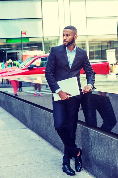 Genç Afrikalı-Amerikalı işadamı sakallı, afro kısa saç, siyah takım elbise, deri ayakkabı, dizüstü bilgisayar, Manhattan'ın Middletown, sokakta ayakta tutan giyen New York'ta seyahat arıyorum bana yardımcı olanvarmı