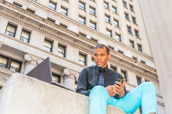 African American businessman with scar on his head, working on laptop computer, texting on phone in New York, Concept of facing reality, up and down, self assured, self esteem, confidence and success.