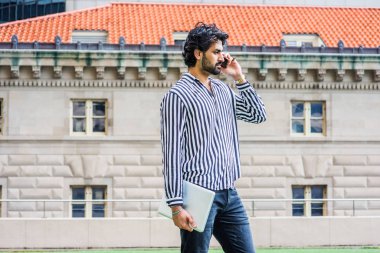 Yağmur günü - grenli, yağmurlu, ıslak hissediyorum. Sakallı, siyah, beyaz çizgili gömlek giyen, elinde dizüstü bilgisayar tutan, New York'ta ofis binasının önünde duran, telefonda konuşan genç işadamı