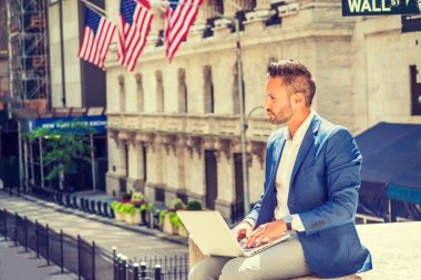 Seyahat, New York City bölgesindeki çalışma, Wall Street işaretiyle bina, dizüstü bilgisayarda çalışarak, düşünme ofis dışında sokakta oturan mavi ceket giyiyor sakallı genç Avrupa iş adamı