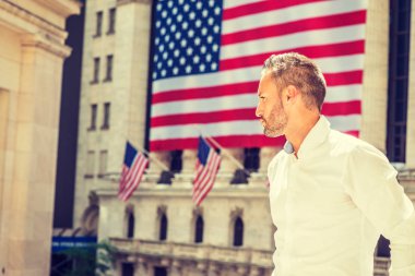 Genç seksi Avrupa uzun kollu beyaz gömlek giymiş sakallı adam New York'ta yaz aylarında seyahat ayakta eski stil office güneş altında Amerikan bayrakları ile bina dışında dört gözle