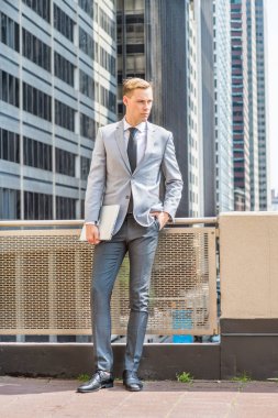 New York 'ta çalışan genç Avrupalı iş adamı, gri ceket, beyaz gömlek, siyah kravat, siyah pantolon, deri ayakkabı, dizüstü bilgisayar, balkonda korkuluk,