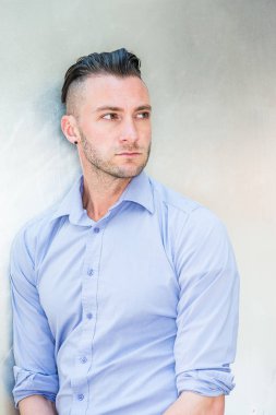 New York'ta genç yakışıklı üniversite öğrencisinin portresi. Genç Ciddi Adam açık mor giyiyor, uzun kollu gömlek, gümüş metal arka plan karşı duran, ileriye dönük, düşünmek