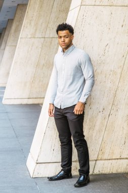 New York'ta Genç Yakışıklı Amerikan Adam Portresi, açık gri uzun kollu gömlek giyiyor, siyah pantolon, deri ayakkabı, sokakta ofis binası dışında duran, güvenle ileriye bakıyor