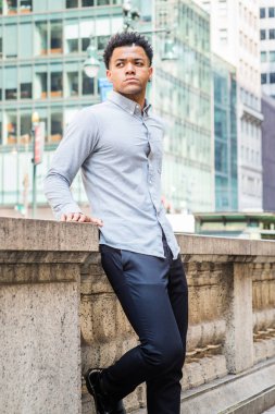New York'ta Genç Yakışıklı Amerikan Adam Portresi, açık gri uzun kollu gömlek giyiyor, siyah pantolon, Manhattan'da sokakta ofis binası dışında yarım duvar tarafından ayakta, ileriye bakıyor