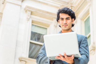 Başarıya giden yol. New York'ta okuyan Young Mix Race American College Student. Koyu mavi ceket giyen, eski tarz ofis binasının dışında oturan, aşağıya bakan, dizüstü bilgisayarda çalışan adam