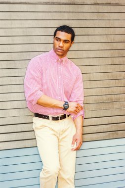 Genç Afro-Amerikan Man kalabalık Times Square seyahat, New York, Denim ceket unbuttoned giyiyor, kırmızı, beyaz desenli gömlek, sarımsı kahverengi pantolon, yürüyüş. Yüksek Binalar, arka planda arabalar.