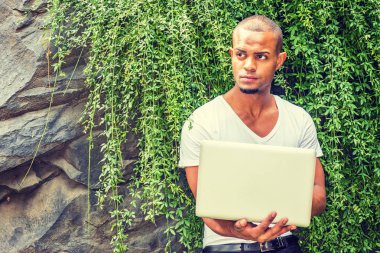 Genç yakışıklı Amerikalı İspanyol dizüstü bilgisayarla çalışıyor. 