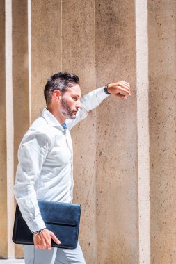 Dışarıyı düşünüyorum. Sakallı, beyaz tişörtlü, evrak çantalı genç Avrupalı iş adamı New York 'ta ofisin dışında güneş ışığı altında duruyor, kolları üzerinde dinleniyor, düşünüyor. Yan Görünüm