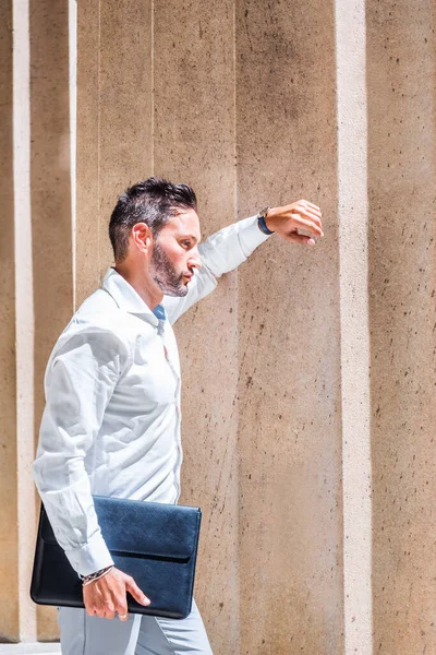 Dışarıyı düşünüyorum. Sakallı, beyaz tişörtlü, evrak çantalı genç Avrupalı iş adamı New York 'ta ofisin dışında güneş ışığı altında duruyor, kolları üzerinde dinleniyor, düşünüyor. Yan Görünüm