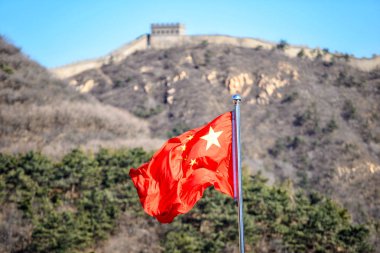 Çin bayrağı ön planda. Arka planda Pekin yakınlarındaki dağlarda büyük Çinli duvar.