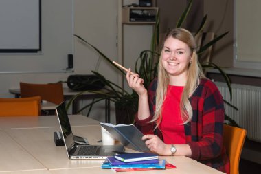 Gülümseyen çay içme ve çalışma bir laptop oturan sarışın kadın.