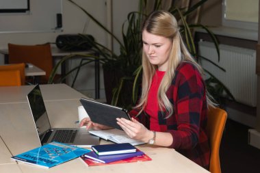 Gülümseyen çay içme ve çalışma bir laptop oturan sarışın kadın.