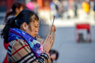 Beijing, Çin - 10 Mart 2016: Tapanların tütsü sopa tutun ve Pekin, Çin Yonghegong Lama Tapınağı'nda dua.