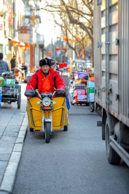 Beijing, Çin - 10 Mart 2016: İnsanlar sokaklarda bisiklet, scooter ve araçların ile ilerliyorsunuz.
