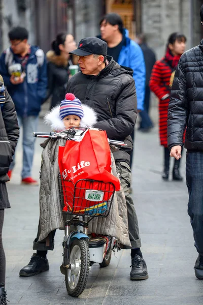 Beijing, Çin - 12 Mart 2016: Bisiklet, scooter ve araçların içinde Beijing sokak. Sokağın ortasında bir adam ve bir çocuk bir scooter üzerinde oturuyor.