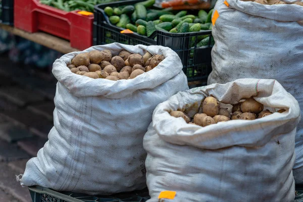 The market sells a variety of vegetables and bags with potatoes.