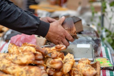 Fırıncı alıcı büyük bir lokma ekmek gösterir..