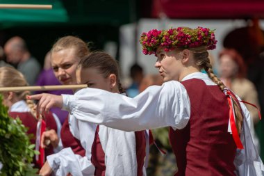 Riga, Letonya - 22 Haziran 2018: yaz gündönümü Pazar. İlginç bir görünümü gösteren bir ele ile ulusal bir kostüm, Genç bir kadın giyinmiş.