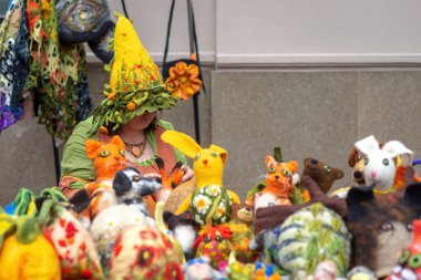 Riga, Letonya - 22 Haziran 2018: yaz gündönümü Pazar. Pamuk renkli keçe şapkalı bir kadın el yapımı yumuşak keçe oyuncak satan.