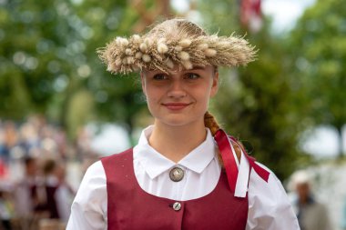 Riga, Letonya - 22 Haziran 2018: yaz gündönümü Pazar. Kameraya bakarak ve gülümseyen bir ulusal kostüm giymiş bir genç kadın.