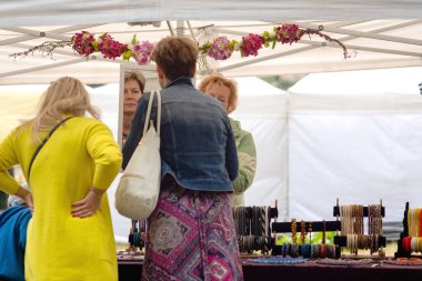 Riga, Letonya - 22 Haziran 2018: yaz gündönümü Pazar. Kadın aynaya yeni takı takdir eder..