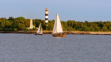 Kanal boyunca deniz feneri tarafından iki Yelkenli tekne sinek.