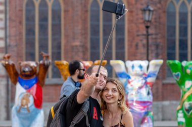 Riga, Letonya - 26 Temmuz 2018: United dostum ayı sergi. Genç insanlar bir çift kendilerini sergi arka plan üzerinde bir telefon ile fotoğraf.