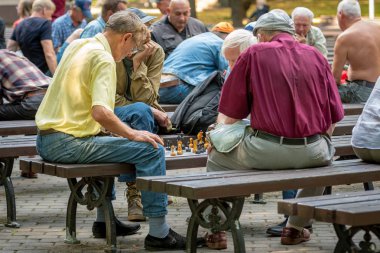 Riga, Letonya - 18 Temmuz 2018: park bankların üzerinde oturan ve satranç oynarken erkekler.