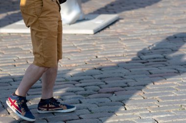 Adamın bacakları şort ve spor ayakkabısı kaldırımda.