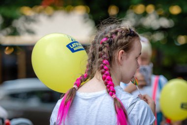 Riga, Letonya - 18 Ağustos 2018: Kız sokakta şeker emme bir balon ile.