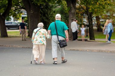 Riga, Letonya - 18 Ağustos 2018: Birkaç yaşlı insanların yürüme ellerini kollarında. Arkadan görüntülemek.