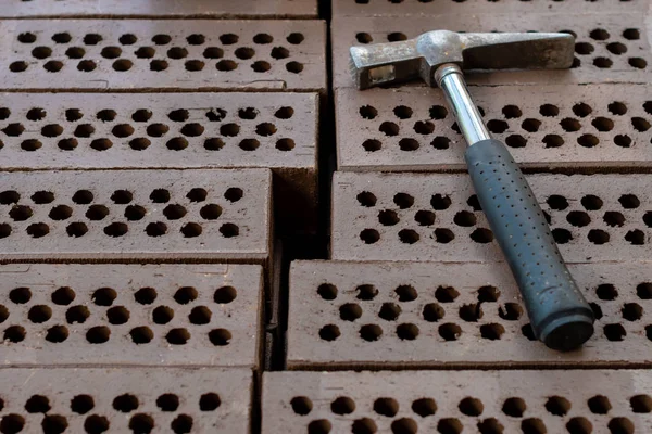 A hammer is laid on a red brick stack.
