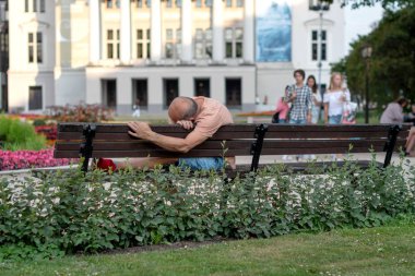 Riga, Letonya - 26 Temmuz 2018: bir orta yaş adam parkta bir bankta yatan.