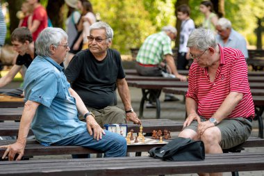 Riga, Letonya - 18 Temmuz 2018: park bankların üzerinde oturan ve satranç oynarken erkekler.