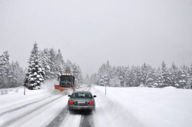 Kar yağışı sonra zor trafik. Kar temizleyici çimentosu karla kaplı dağ yolu temizler.