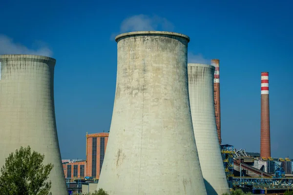 Modern power station cooling towers against a blue sky.